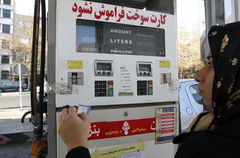 An Iranian woman uses a fuel smart card at a gas station in Tehran (AFP)